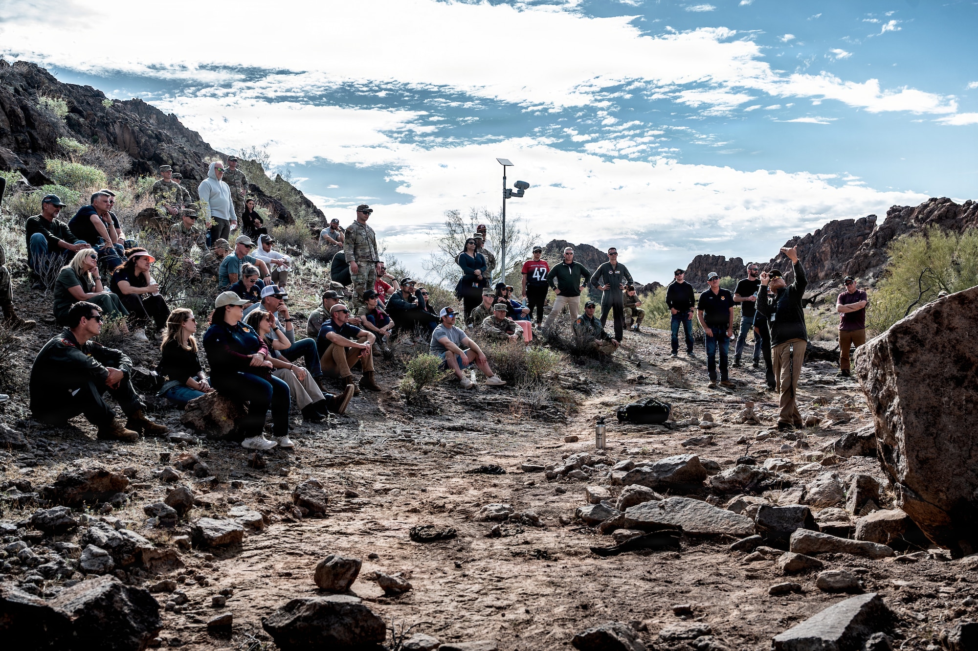 Akoni Mirafuentes, 56th Operations Support Squadron aircrew flight equipment continuation instructor, demonstrates the use of a signal mirror for 56th Fighter Wing honorary commanders, Jan. 22, 2026, at the Barry M. Goldwater Range, Arizona. The demonstration focused on survival, evasion, resistance, and escape skills required for pilots to communicate with overhead aircraft and survive in remote environments. These survival disciplines ensure pilots remain recoverable, directly supporting the 56th FW’s ability to project persistent airpower. (U.S. Air Force photo by Airman 1st Class Belinda Guachun-Chichay)
