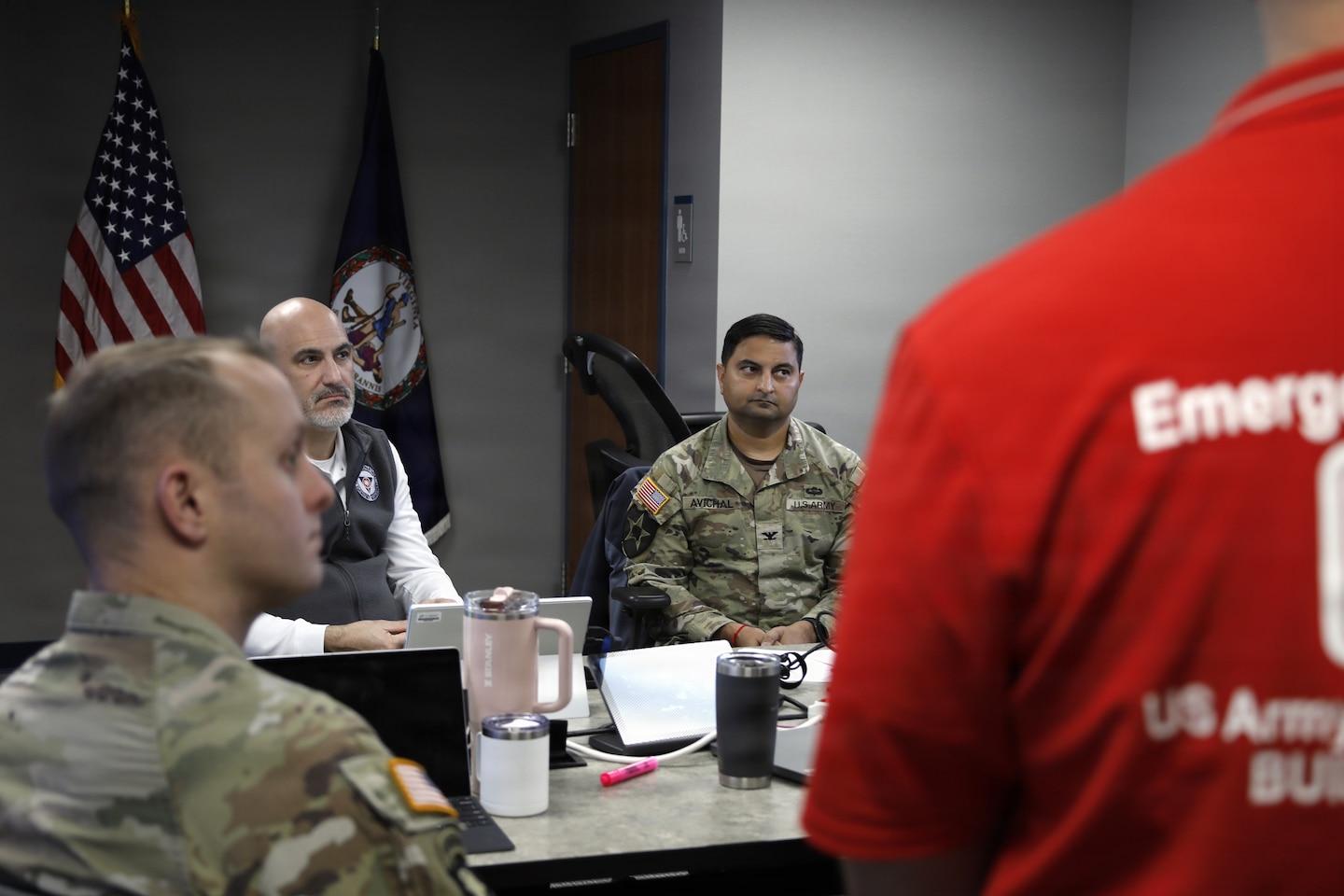 Two Soldiers and a another man are seen sitting at a conference room table.