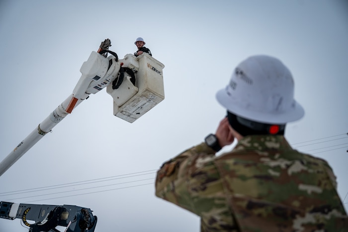 U.S. Air Force Staff Sgt. Austin Frerichs, 773d Civil Engineer Squadron electrical systems craftsman, calls out to Isaac Larock, an electrical systems crew leader, while he operates the aerial lift of a utility truck at Joint Base Elmendorf-Richardson, Alaska, Jan. 26, 2026. The 773d CES electrical team is on standby 24 hours a day, seven days a week, to respond without hesitation during adverse weather and ensure mission readiness. (U.S. Air Force photo by Senior Airman Hunter Hites)