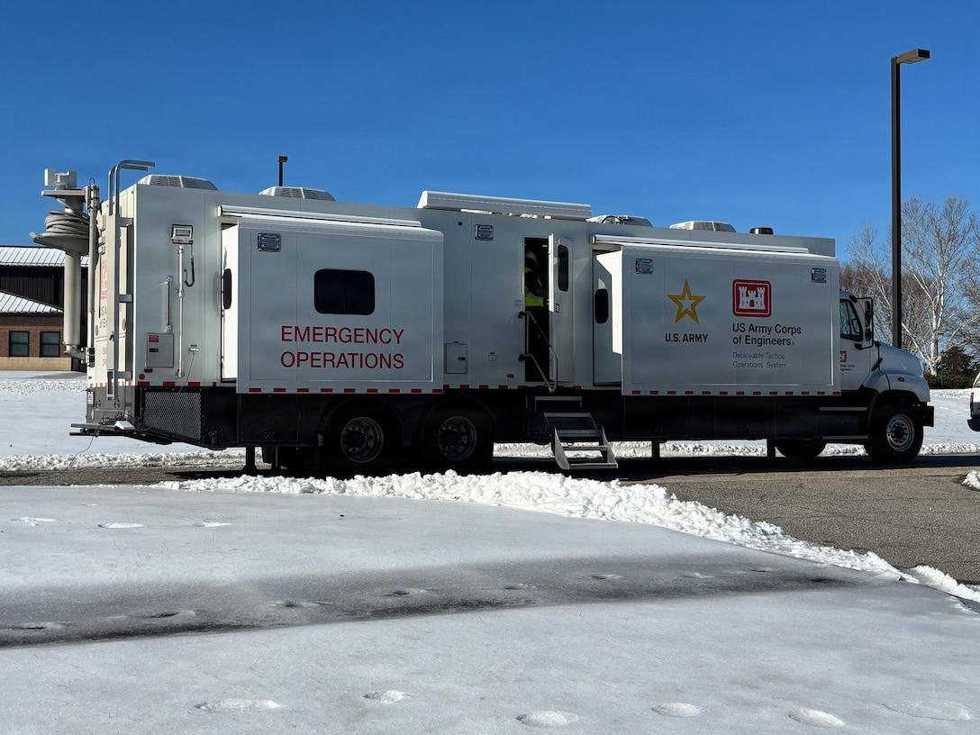 A large truck is parked in a parking lot that is surrounded by snow and ice.