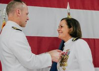VIRGINIA BEACH, Virginia (Aug. 28, 2025) - Capt. David Cox, chief of staff, commander, Submarine Force, U.S. Pacific Fleet, left, presents an award to Capt. Stephany Moore, outgoing commanding officer, commander, Undersea Surveillance (CUS), right, during a change of command ceremony for CUS held at the Center for Naval Aviation Technical Training Unit in Virginia Beach, Virginia, Aug. 28, 2025. During the ceremony, Capt. Steven Lawrence, from Bridgeport, Pennsylvania, relieved Moore, from Caledonia, New York as commander of CUS. CUS provides global maritime acoustic surveillance and timely, accurate anti-submarine warfare (ASW) reporting using persistent, long-range, fixed and mobile systems. (U.S. Navy photo by Yeoman 1st Class Nikolas Cantu)