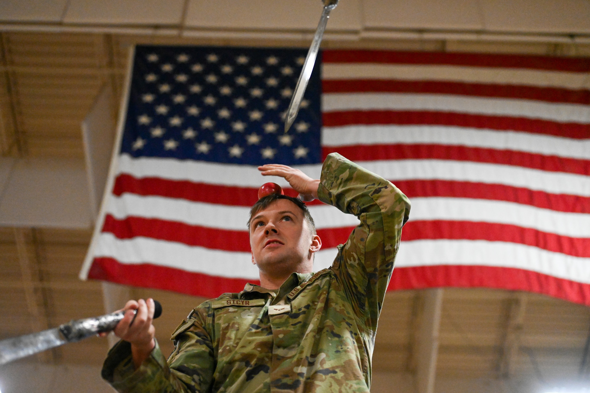 Senior Airman Rick Stcyr balances an apple on his head while simultaneously juggling knives on Joint Base Elmendorf-Richardson, Alaska, Dec. 2, 2025. Stcyr’s unique ability to engage and handle these dangerous performances helps him mentally equip himself for the high intensity situations being an Airmen sometimes presents. (U.S. Air Force photo by Airman 1st Class Eli A. Rose)