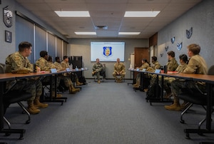 U.S. Air Force Col. Kind, 97th Air Mobility Wing (AMW) commander, left, and Chief Master Sgt. Jonny Adams, 97th AMW command chief, right, explains the Wing priorities to Airmen participating in the First Term Enlisted Course (FTEC) at Altus Air Force Base, Oklahoma, Jan. 12, 2026. The 97th AMW command team briefed the FTEC participants on the Wing’s mission, base resources, safety protocol, and professional development opportunities. (U.S. Air Force Photo by Airman 1st Class Emma Wright)