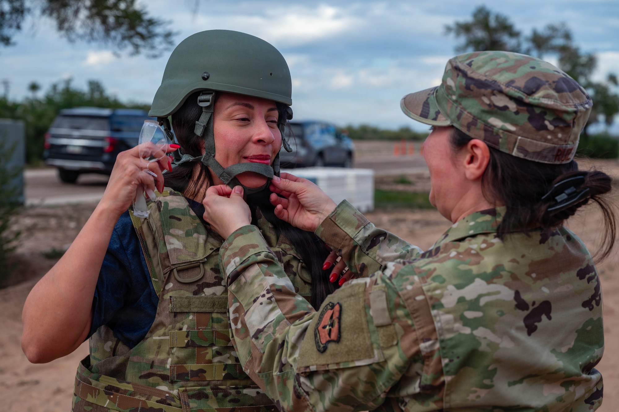 U.S. Air Force Master Sgt. Angela Ruiz, 56th Public Affairs chief of community relations, helps Elizabeth Canchola, 310th Fighter Squadron honorary commander, put on a helmet, Jan. 22, 2026, at Gila Bend Air Force Auxiliary Field, Arizona. HCCs took part in a simulated deployment, which replicated aspects of a deployed environment, allowing honorary commanders to experience the pace and structure of mission operations. Throughout the simulation, HCCs took part in briefings, operational activities, and direct engagement engaged directly with Airmen across the base.  (U.S. Air Force photo by Airman 1st Class Tekorey Watkins)