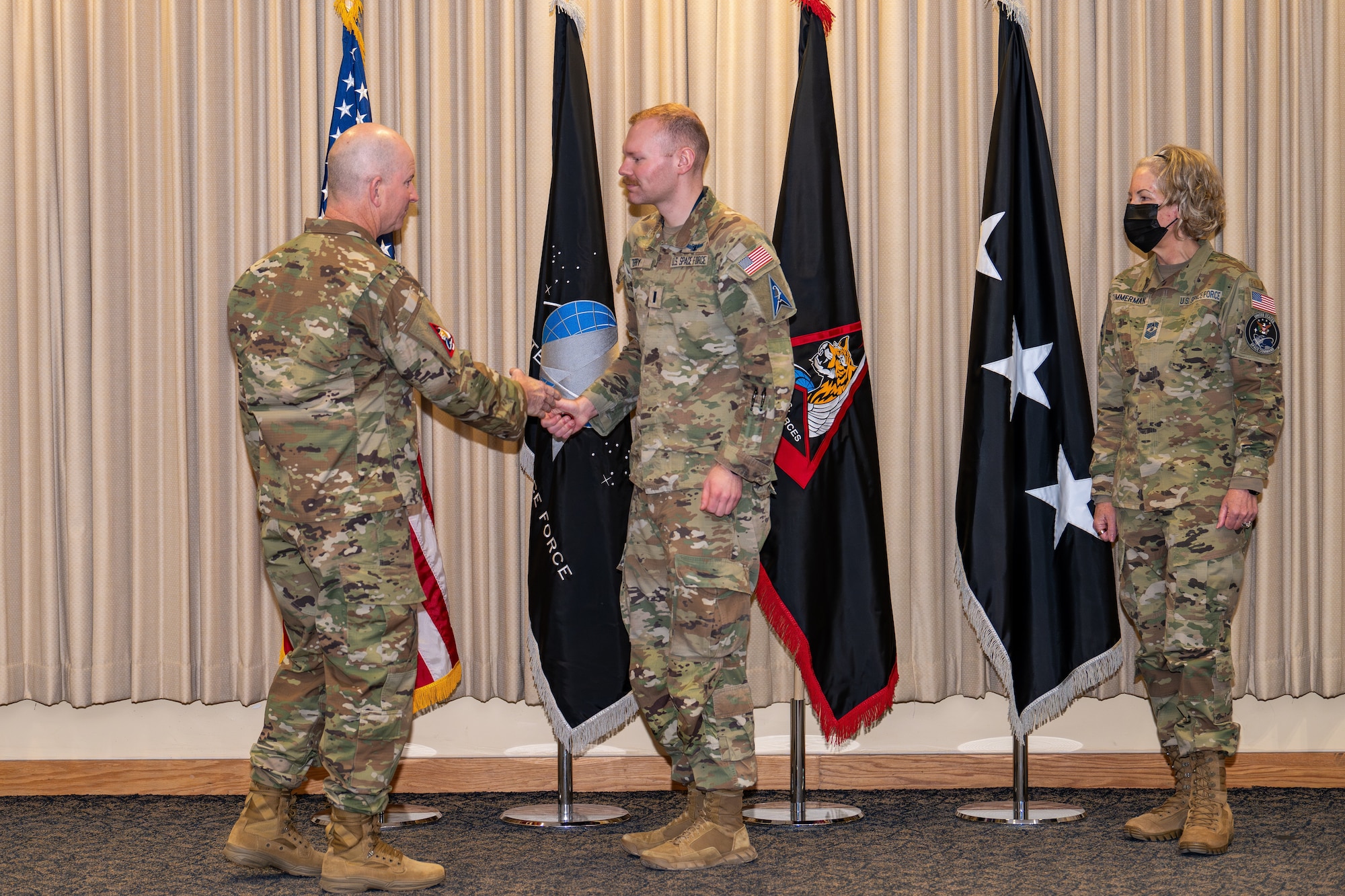 Soldier shakes hands with general in an auditorium