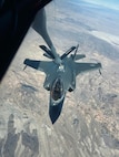 An F-35A Lighting II is in position for an air refueling with a desert landscape in the background.