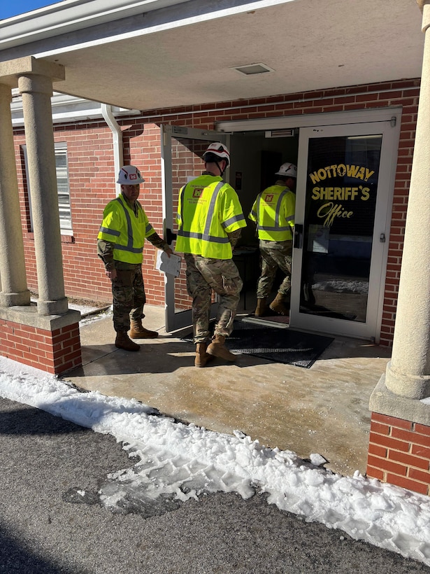 Three Soldiers are in single file going into the front door of the Nottoway County Sheriffs Office.