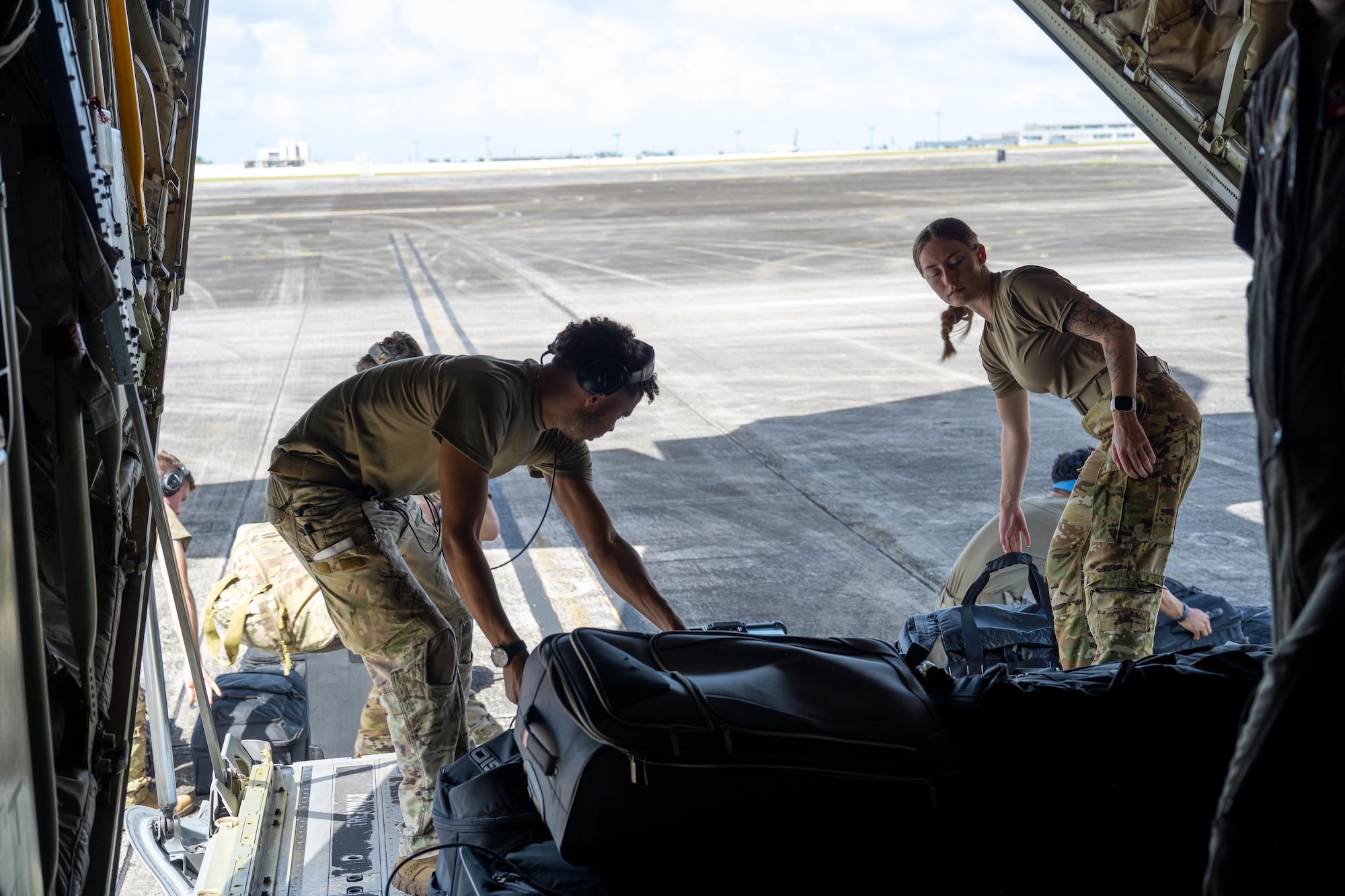 U.S. Air Force Senior Airman Carson Douglas, left, 40th Airlift Squadron loadmaster, left, and Senior Airman Sophia Johnson, 39th Airlift Squadron loadmaster, offload luggage from a C-130J Super Hercules assigned to the 317th Airlift Wing at Won Pat International Airport, Guam, Jan. 15, 2026. Loadmasters manage aircraft weight and balance, secure cargo, and monitor in-flight conditions to ensure safe and efficient airlift operations. (U.S. Air Force photo by Airman 1st Class Adrien Tran)