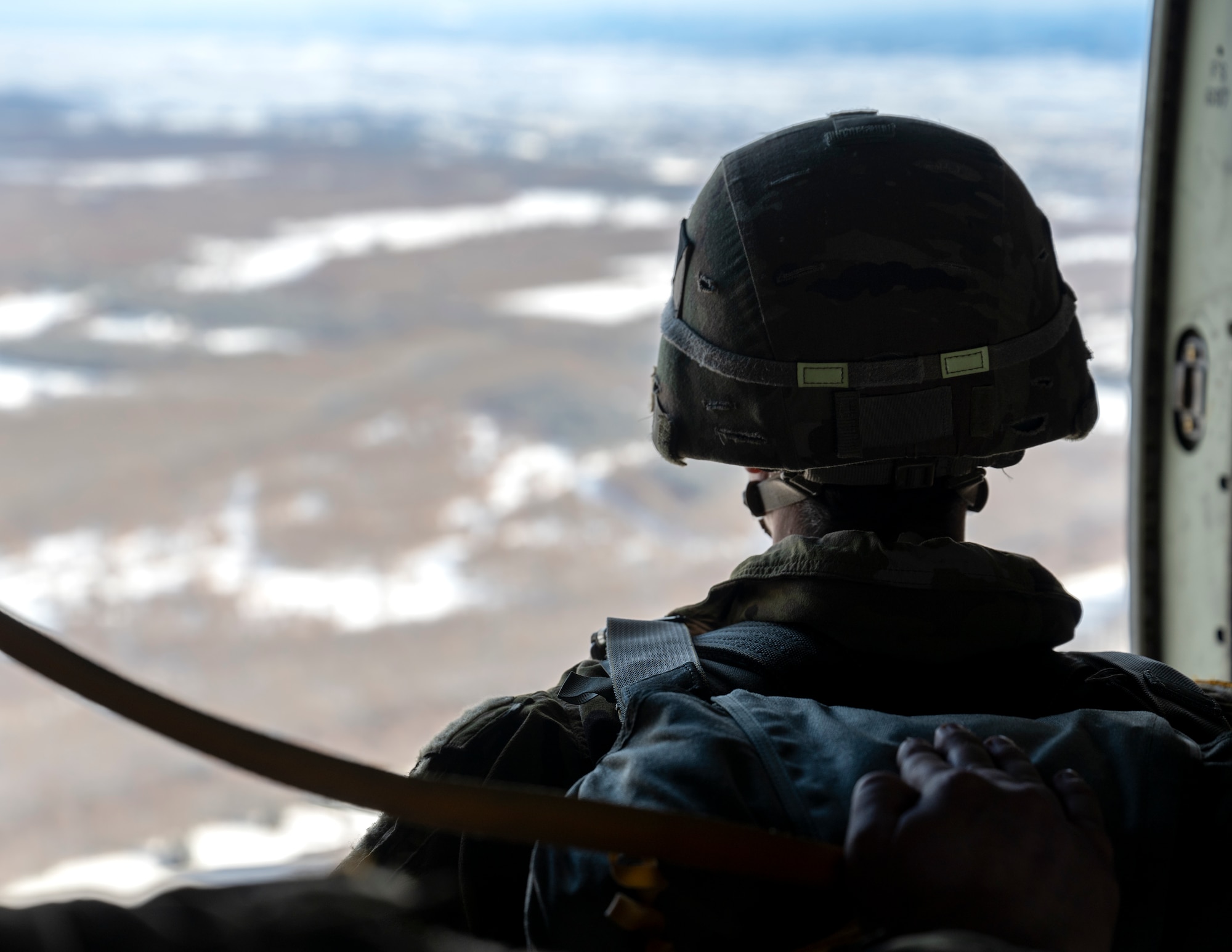A U.S. Army paratrooper assigned to the 11th Airborne Division, 2nd Brigade, looks out the troop door of a C-130J Super Hercules before executing a static line jump during exercise North Wind 26.