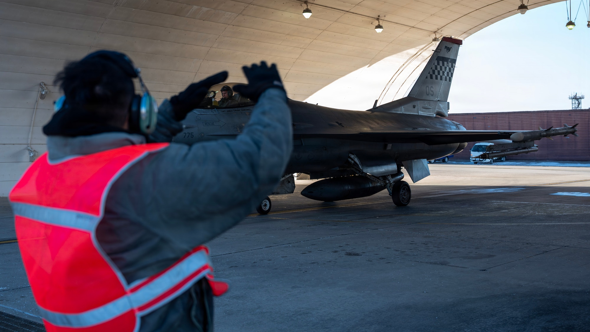 U.S. Air Force Senior Airman Daniel Romero, 35th Fighter Generation Squadron crew chief, marshals an F-16 Fighting Falcon during a hot-pit refueling operation Osan Air Base, Republic of Korea, Jan. 27, 2026. Hot-pit refueling allows F-16s to land, refuel with engines running, and return to the air within minutes, sustaining Osan’s ability to fight tonight. ((U.S. Air Force photo by Staff Sgt. Sarah Williams)