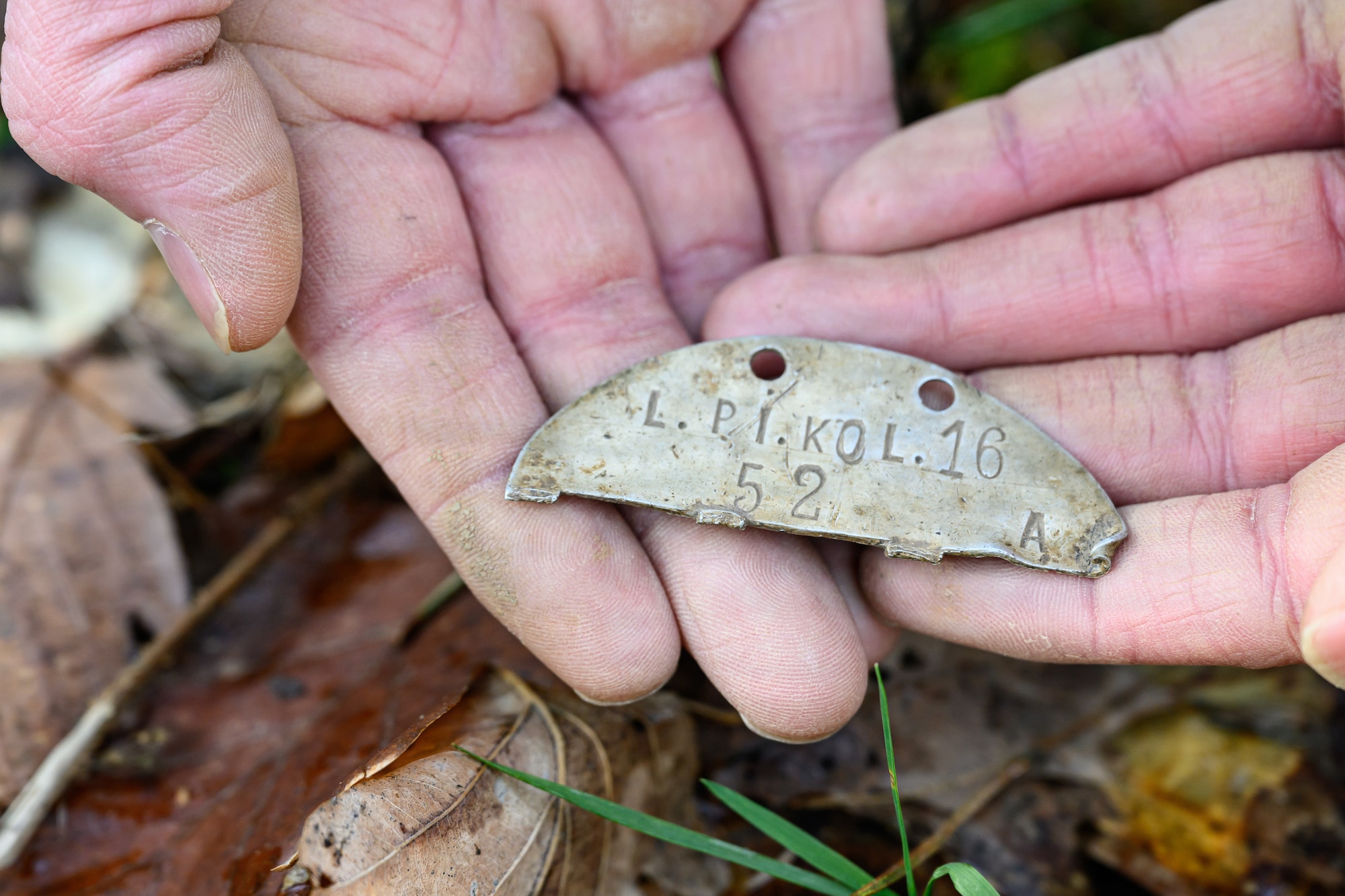 A person holds up an old metal dog tag he found while metal detecting