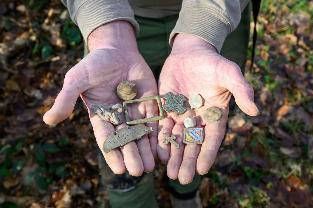 A person holds up a handful or artifacts found while metal detecting.