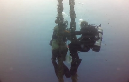 U.S. Navy Seabee divers, assigned to Underwater Construction Team One (UCT 1) Construction Dive Detachment Bravo (CDD/B), clean a riser chain in order to visually inspect and take measurements during a dive at the NATO Marathi Pier Complex in Souda Bay, Greece,  Dec. 9, 2025.
