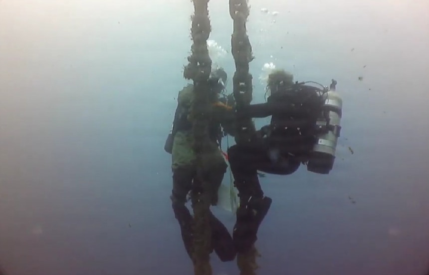 U.S. Navy Seabee divers, assigned to Underwater Construction Team One (UCT 1) Construction Dive Detachment Bravo (CDD/B), clean a riser chain in order to visually inspect and take measurements during a dive at the NATO Marathi Pier Complex in Souda Bay, Greece,  Dec. 9, 2025.
