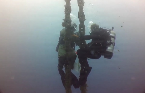U.S. Navy Seabee divers, assigned to Underwater Construction Team One (UCT 1) Construction Dive Detachment Bravo (CDD/B), clean a riser chain in order to visually inspect and take measurements during a dive at the NATO Marathi Pier Complex in Souda Bay, Greece,  Dec. 9, 2025.