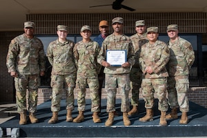 People in military uniforms pose for a group photo.