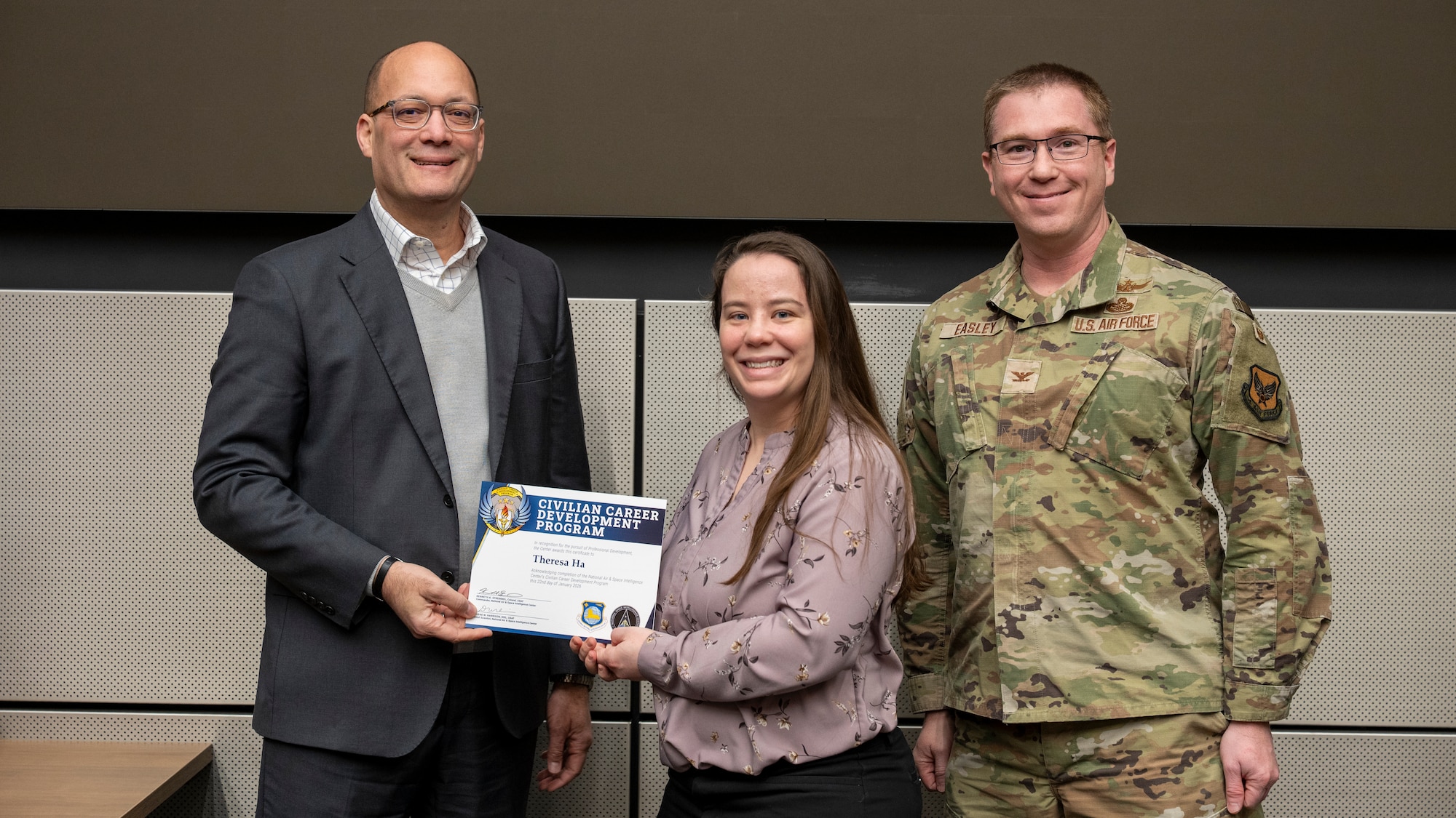 Duane Harrison, left, and Col. Shaun Easley, award a certificate to Theresa Ha.