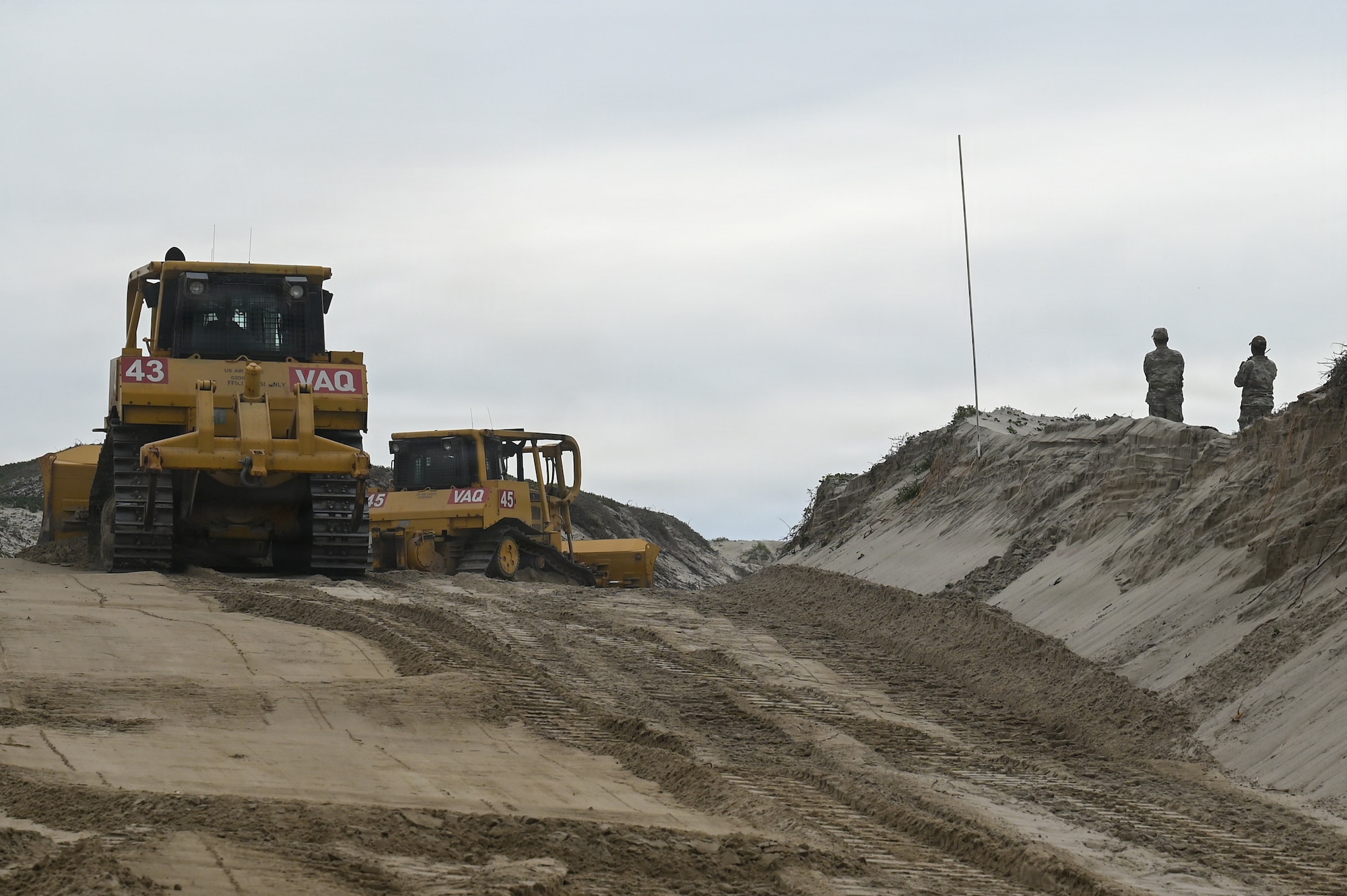 Two bulldozers smooth out sand on a dune during the dune restoration project at Vandenberg Space Force Base.