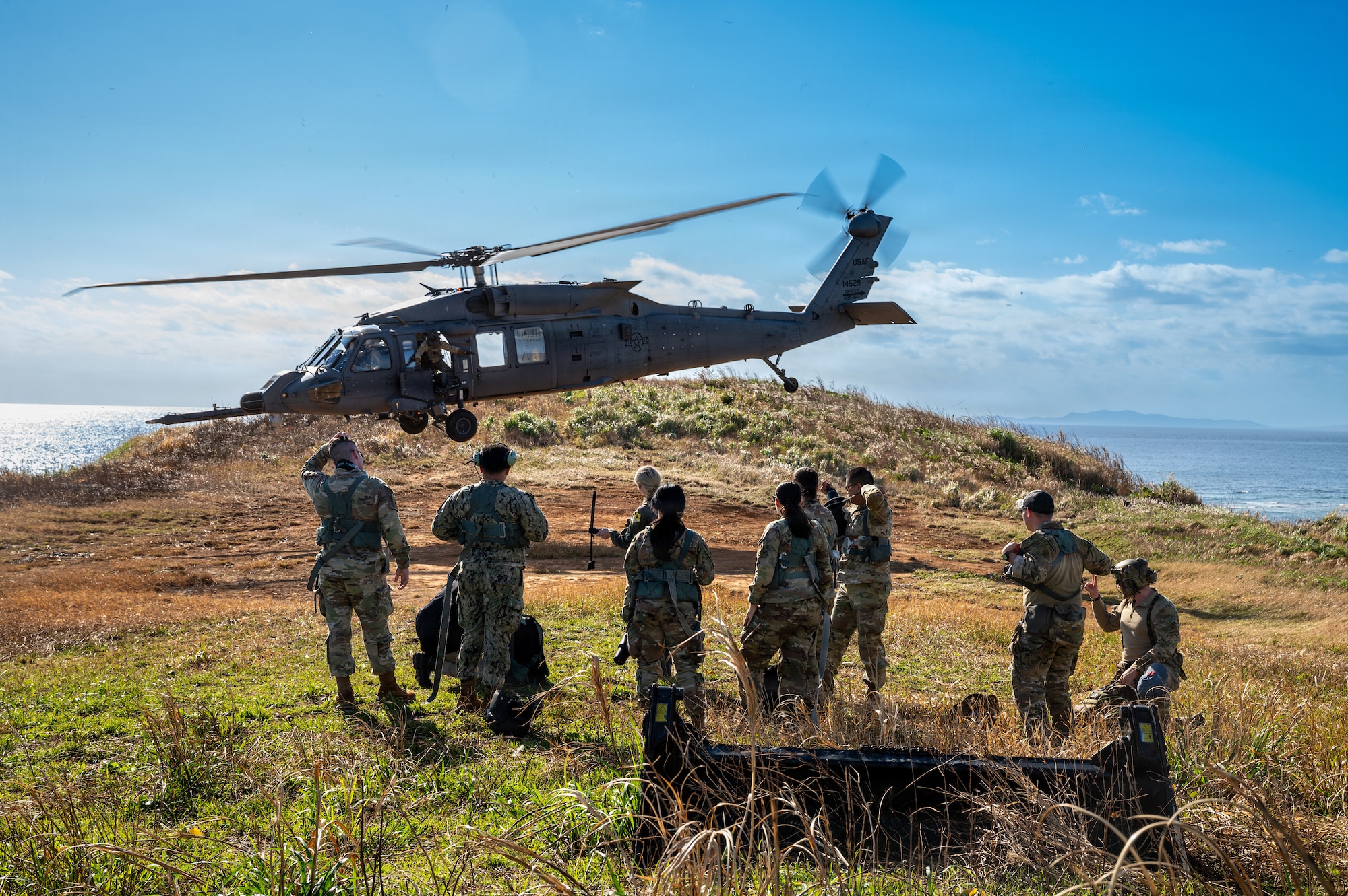 Service members watch a helicopter take off.