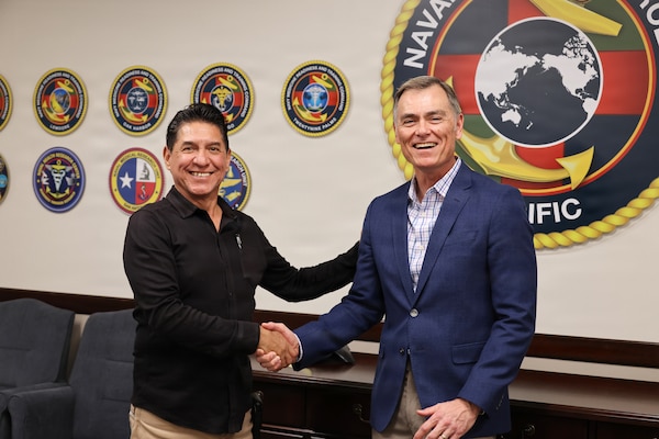 Dr. Michael McGinnis, executive director for the Navy’s Bureau of Medicine and Surgery and director of Navy Medicine’s Civilian Corps, presents a coin to Mr. Robert Villalobos, an information technology specialist at Naval Medical Forces Pacific (NMFP) Jan. 26, 2026. Villalobos was recognized for his significant, long-term impact on command morale as the Recreation Fellowship Committee Chair for the past 13 years, with his efforts being credited as a primary reason for the command's consistently positive climate. (DoW photo by Regena Kowitz/Released)
