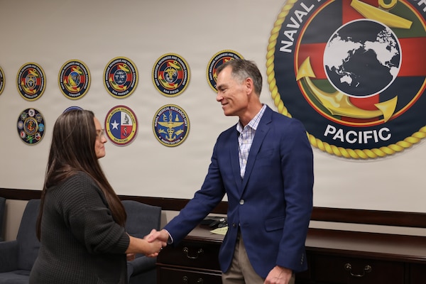 Dr. Michael McGinnis, executive director for the Navy’s Bureau of Medicine and Surgery and director of Navy Medicine’s Civilian Corps, presents a coin to Ms. Paula Curielabreu, a manpower analyst at Naval Medical Forces Pacific (NMFP), Jan. 26, 2026. Curielabreu was recognized as the NMFP Civilian of the Year for fiscal year 2025 for her transformative contributions, which included streamlining manpower processes and leading a training roadshow for 10 subordinate commands that resulted in a better-prepared workforce. (DoW photo by Regena Kowitz/Released)