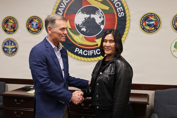 Dr. Michael McGinnis, executive director for the Navy’s Bureau of Medicine and Surgery and director of Navy Medicine’s Civilian Corps, presents a coin to Ms. Maria Lourdes Gregorio, the executive secretary for Naval Medical Forces Pacific (NMFP) Jan. 26, 2026. Gregorio, a plank owner of the command and a civil servant with Navy Medicine for more than 25 years, was recognized for her sustained superior performance and dedication. She has been instrumental in the success of numerous command events and has earned multiple accolades for her flawless management of the command's travel program. (DoW photo by Regena Kowitz/Released)