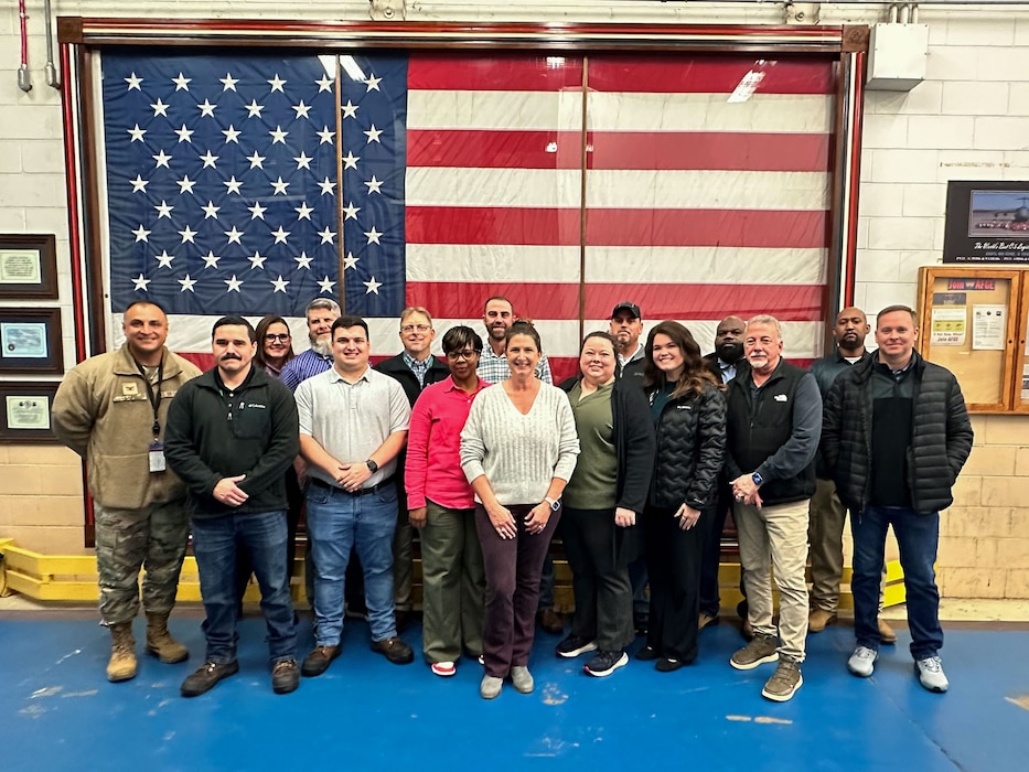 a group of people smile at the camera with an American flag prominently displayed in the background