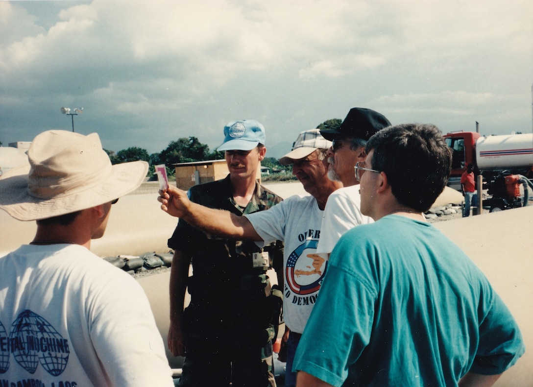 Five men stand in a circle, looking at a water test.