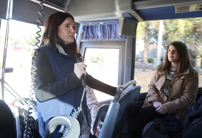 Lady standing giving a tour on a bus.