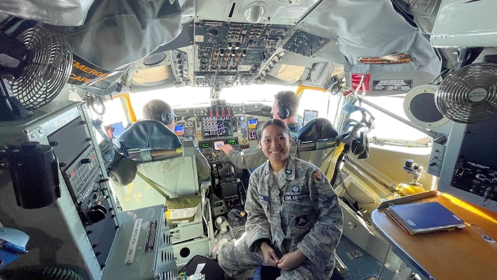 A female cadet poses for a photo in a cockpit