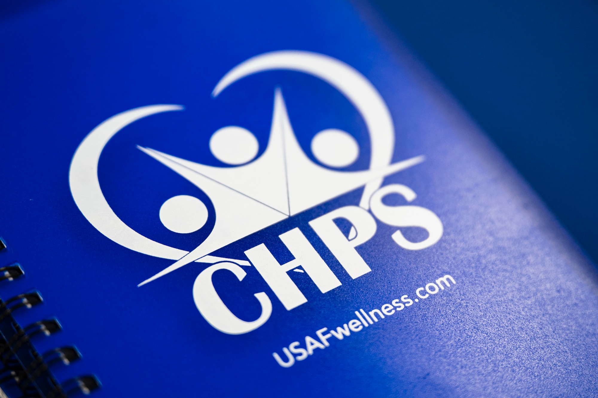 A blue notebook with a logo and "CHPS" "USAFwellness.com" is pictured.