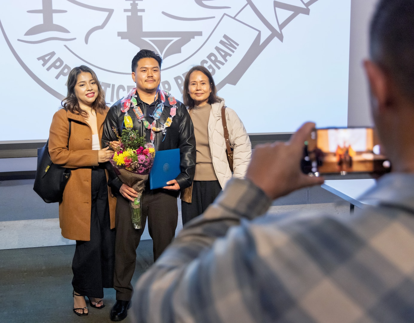 Nutchapol Williams, production machinery electrician, PSNS & IMF San Diego Detachment, poses for photos with family, Jan. 22, 2026, following the 2026 Southwest Regional Apprentice Program graduation ceremony at Southwestern College, Chula Vista, California. (U.S. Navy photo by Wendy Hallmark)