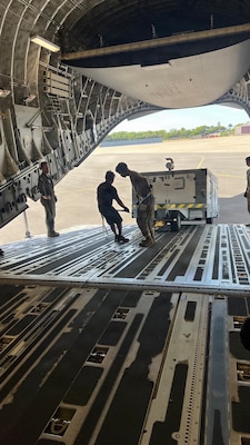 Airmen from the 48th Aerial Port Squadron and the 735th Air Mobility Squadron load cargo onto an aircraft at Joint Base Pearl Harbor-Hickam, Hawaii, Nov. 13, 2025.