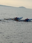 The backend of an outrigger canoe sticks out the top of the water. Partially submerged, a grey hazy sky liters the background.