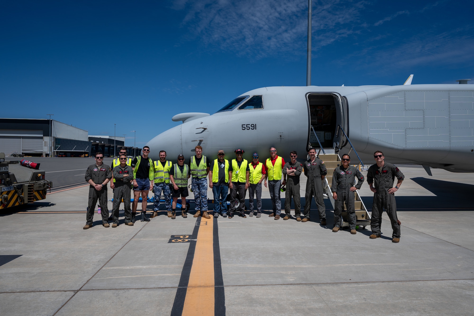 U.S. Air Force Contracted Logistics Support Airmen and Royal Australian Air Force MC-55A maintenance team Airmen pose next to a USAF EA-37B Compass Call and its aircrew members at Royal Australian Air Force Base Edinburgh, Dec. 9, 2025. The teams trained together in preparation for the RAAF receiving its own version of a Gulfstream-based special mission support aircraft. (U.S. Air Force courtesy photo)