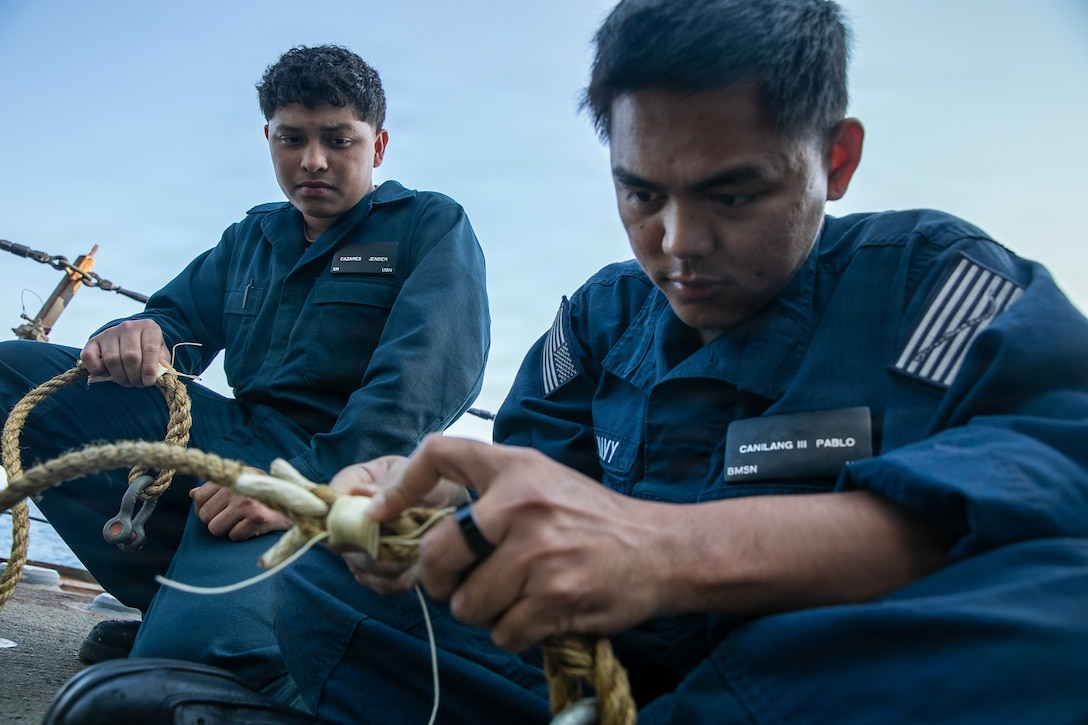U.S. Navy Boatswain’s Mate Seaman Pablo Canilang, right, and Seaman Jender Cazares repair rope on the starboard weather deck of the Arleigh Burke-class guided-missile destroyer USS Mitscher (DDG 57), Jan. 26, 2025. Mitscher is deployed to the U.S. 5th Fleet area of operations to support maritime security and stability in the U.S. Central Command area of responsibility.