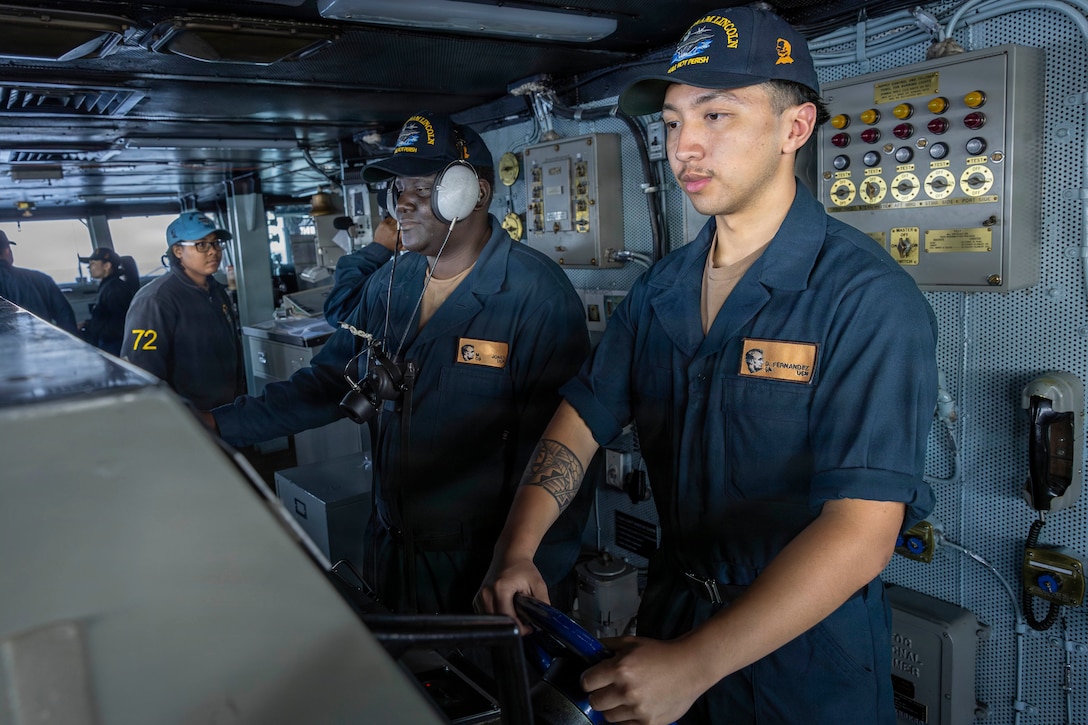 U.S. CENTRAL COMMAND AREA OF RESPONSIBILITY (Jan. 27, 2026) U.S. Navy Seaman Dominic Fernandez, front, and U.S. Navy Operations Specialist Seaman Marquis Jones stand watch as helmsman and lee helmsman on the bridge aboard the Nimitz-class aircraft carrier USS Abraham Lincoln (CVN 72) in the U.S. Central Command (CENTCOM) area of responsibility, Jan. 27. Abraham Lincoln is deployed to the U.S. 5th Fleet area of operations to support maritime security and stability in the CENTCOM area of responsibility. (U.S. Navy photo by Mass Communication Specialist Seaman Samuel Evarts)