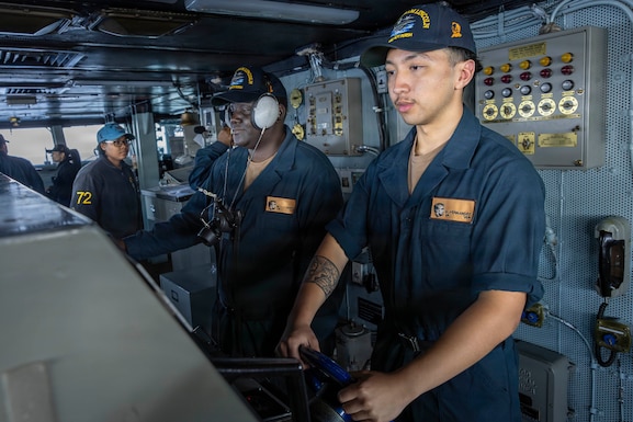 U.S. CENTRAL COMMAND AREA OF RESPONSIBILITY (Jan. 27, 2026) U.S. Navy Seaman Dominic Fernandez, front, and U.S. Navy Operations Specialist Seaman Marquis Jones stand watch as helmsman and lee helmsman on the bridge aboard the Nimitz-class aircraft carrier USS Abraham Lincoln (CVN 72) in the U.S. Central Command (CENTCOM) area of responsibility, Jan. 27. Abraham Lincoln is deployed to the U.S. 5th Fleet area of operations to support maritime security and stability in the CENTCOM area of responsibility. (U.S. Navy photo by Mass Communication Specialist Seaman Samuel Evarts)