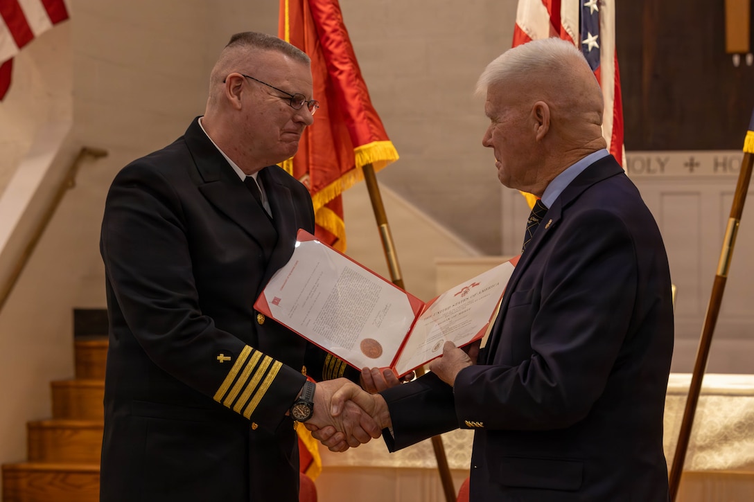 Retired U.S. Marine Corps Maj. Gen. Tom Braaten, right, presents U.S. Navy Capt. William S. Riley, command chaplain for Marine Corps Installations-East, with a Legion of Merit award during a retirement ceremony at Marine Corps Base Camp Lejeune, North Carolina, Jan. 26, 2026. Riley served in a wide range of duty assignments across the United States and overseas, including operational and leadership roles supporting Marines and Sailors. Riley concluded his military service in 2026 as the command chaplain for Marine Corps Installations East. (U.S. Marine Corps photo by Lance Cpl. Erica S. Padgett)