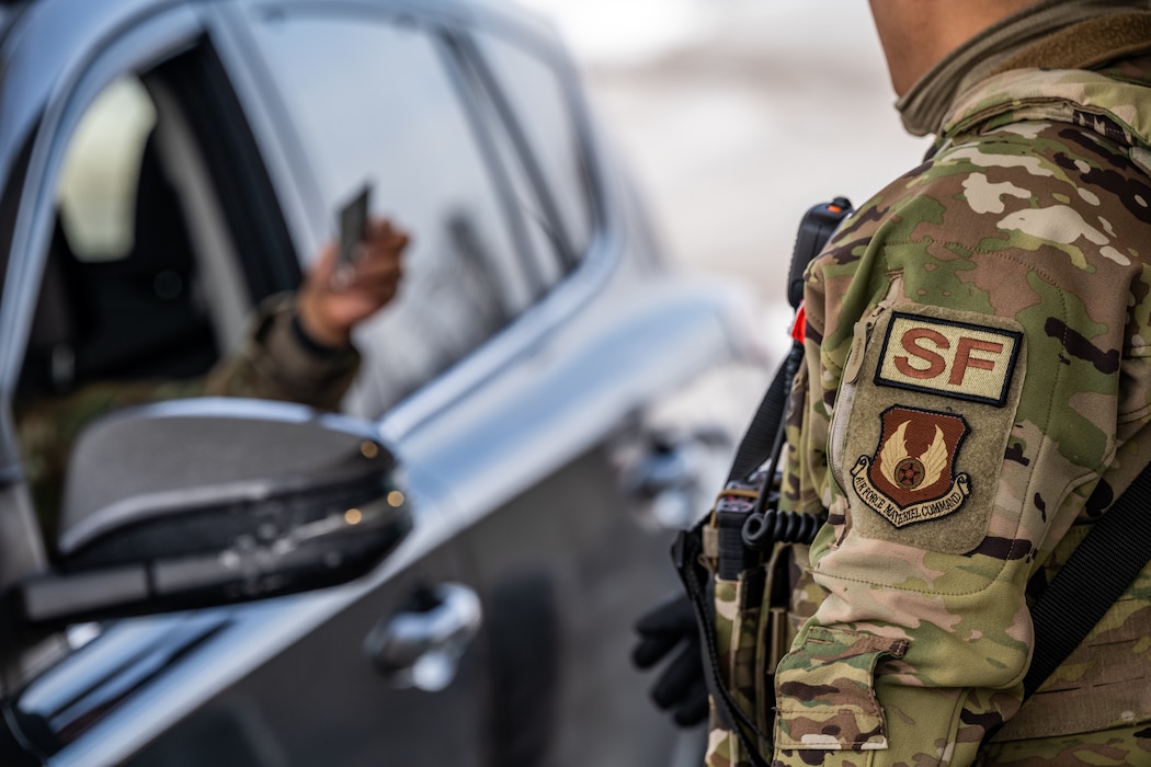 Close up image of a camouflage military uniform arm scanning an ID card. An "SF" and Air Force Materiel Command patch are adhered to sleeve