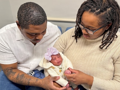 Husband and Wife holding newborn baby between them.