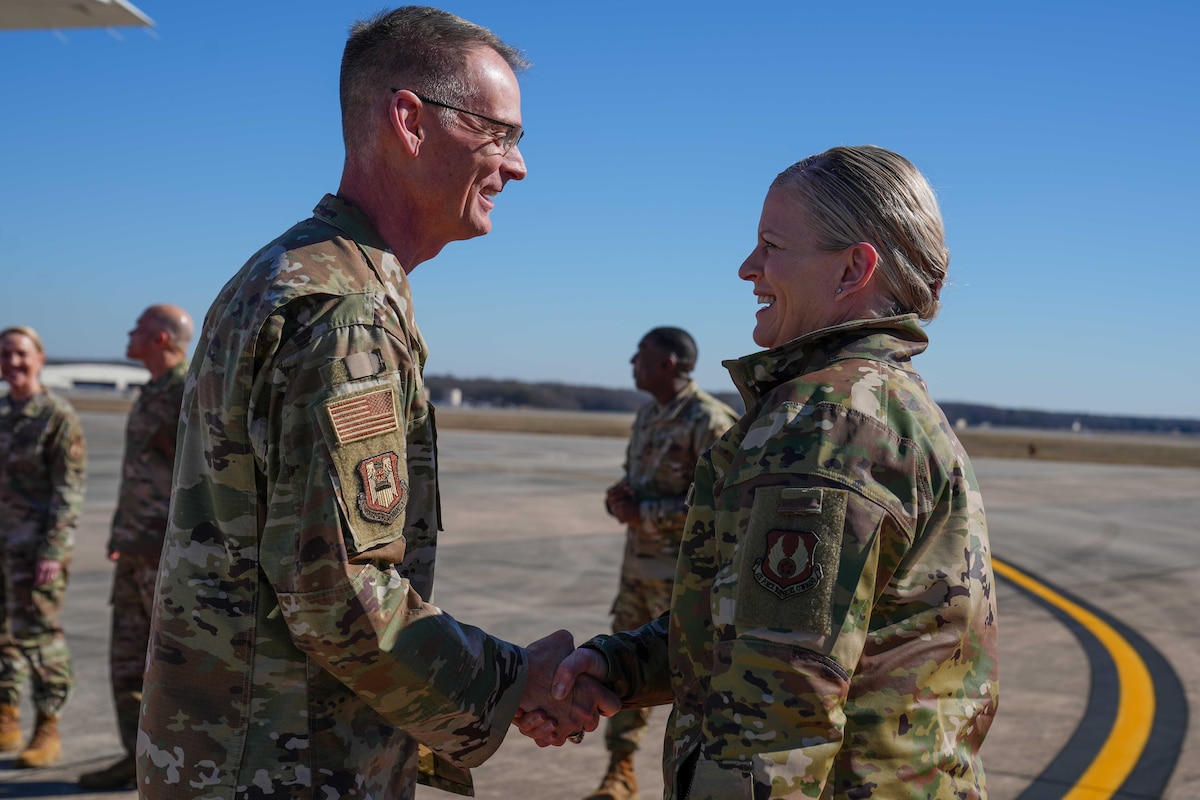 Photo shows two people shaking hands on flight line.