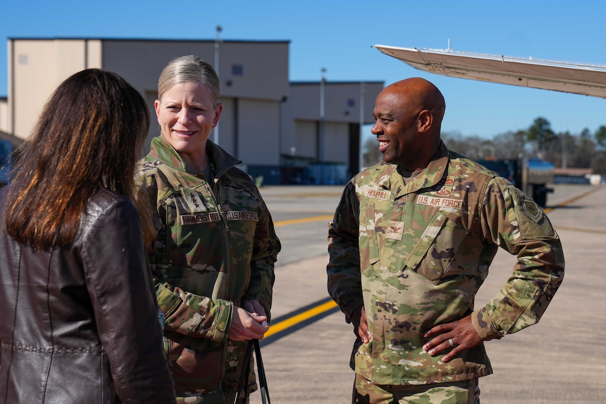 Photo shows group of people speaking to one another on flight line.