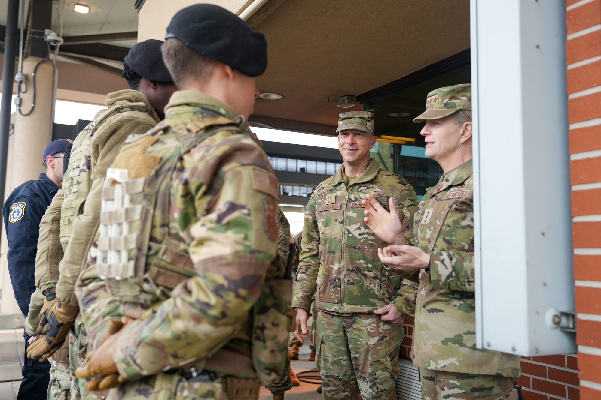 Photo shows group of uniformed individuals speaking to each other outside building.