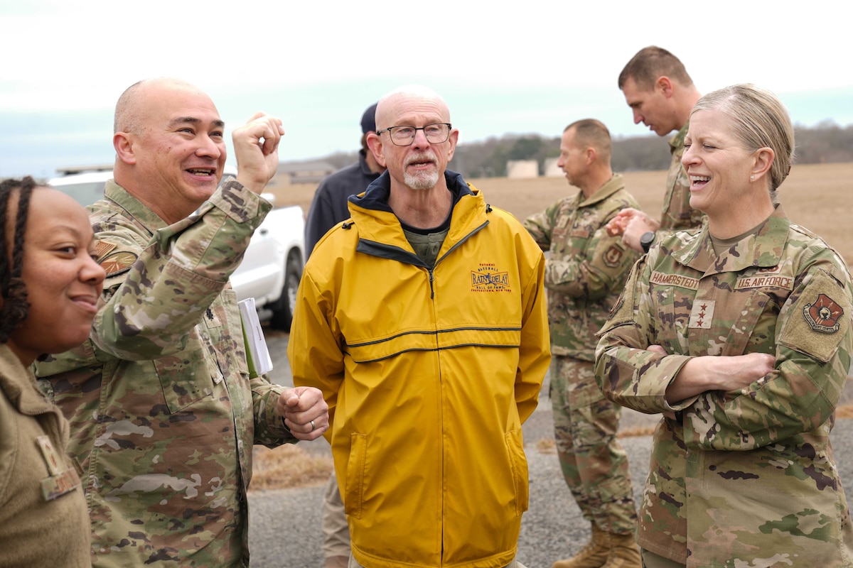Photo shows group of people speaking outdoors.