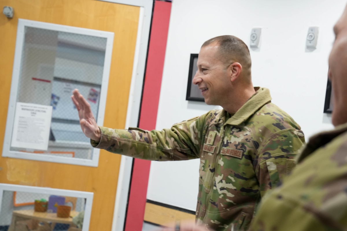 Photo shows man in uniform smiling and waving.