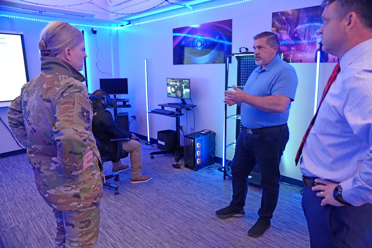 Photo shows people speaking next to an individual using a VR set.