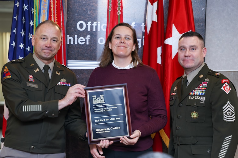 Two soldiers present a woman with a plaque.