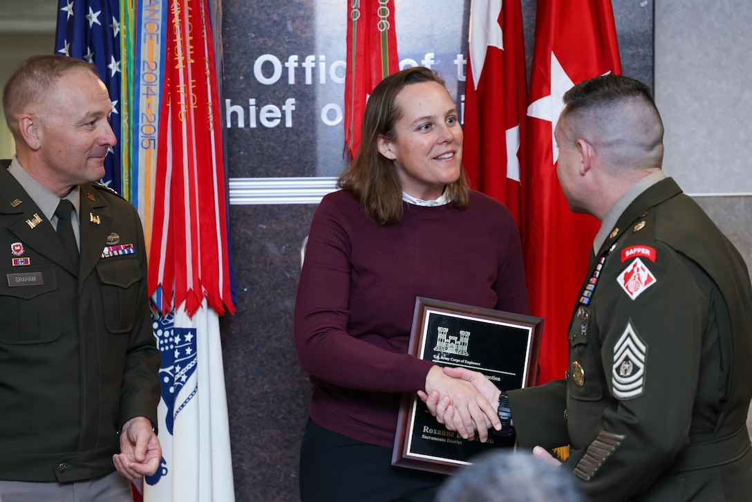 Two soldiers present a woman with a plaque.