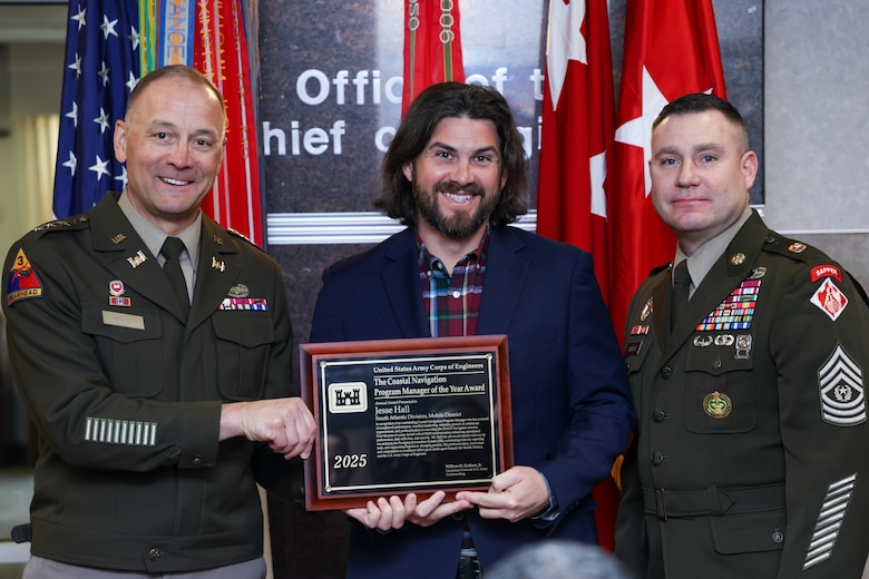 Two soldiers present a man with a plaque.
